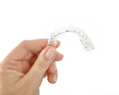 Hand holding up tray of clear aligners in Champaign, IL