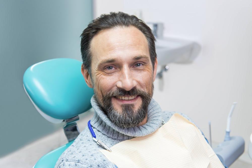 man smiling in dental chair after getting a filling