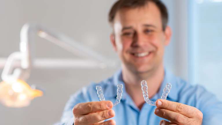 Dentist holding up clear aligners in Champaign, IL