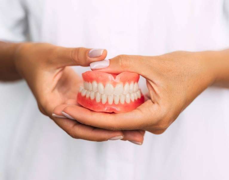 Woman holding dentures in champaign