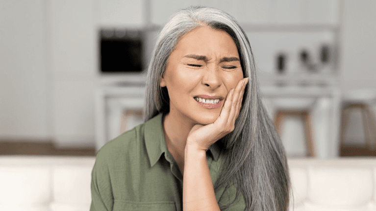 woman holding her left cheek while in pain