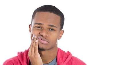Man holding face in pain from dental emergency near Champaign, IL