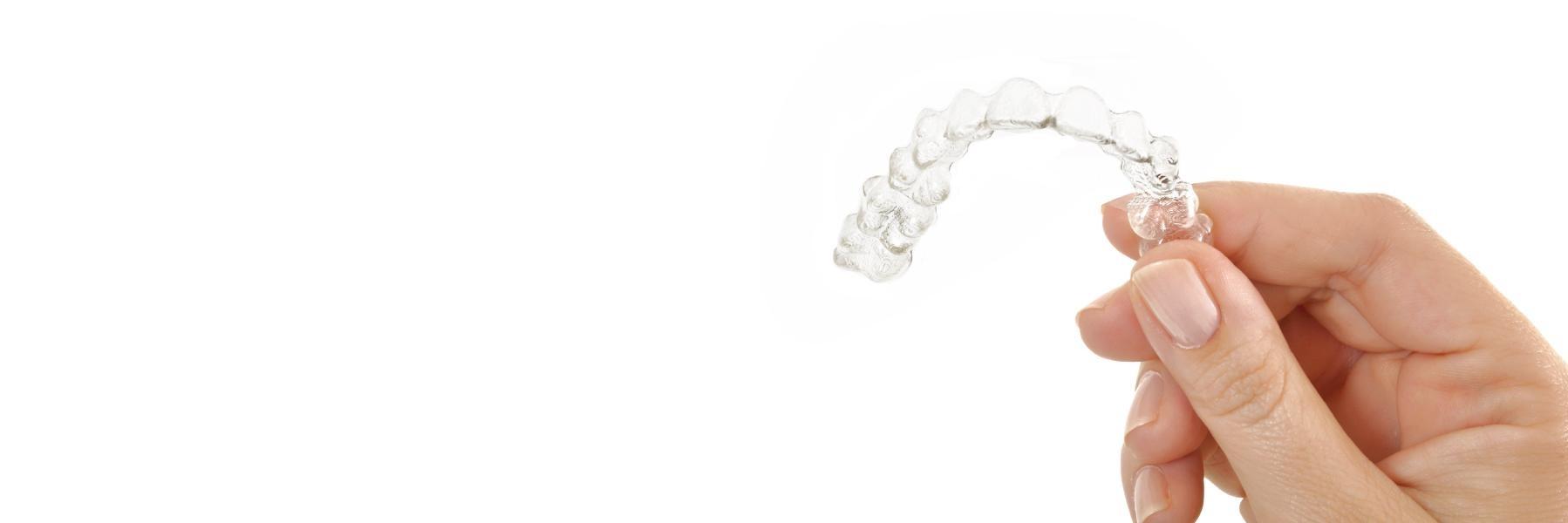 Hand holding up tray of SureSmile clear braces in Champaign, IL
